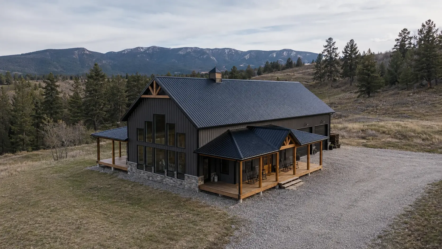 Barndominium with black vertical metal siding, a standing seam roof, timber-post covered porches, and a stone skirt